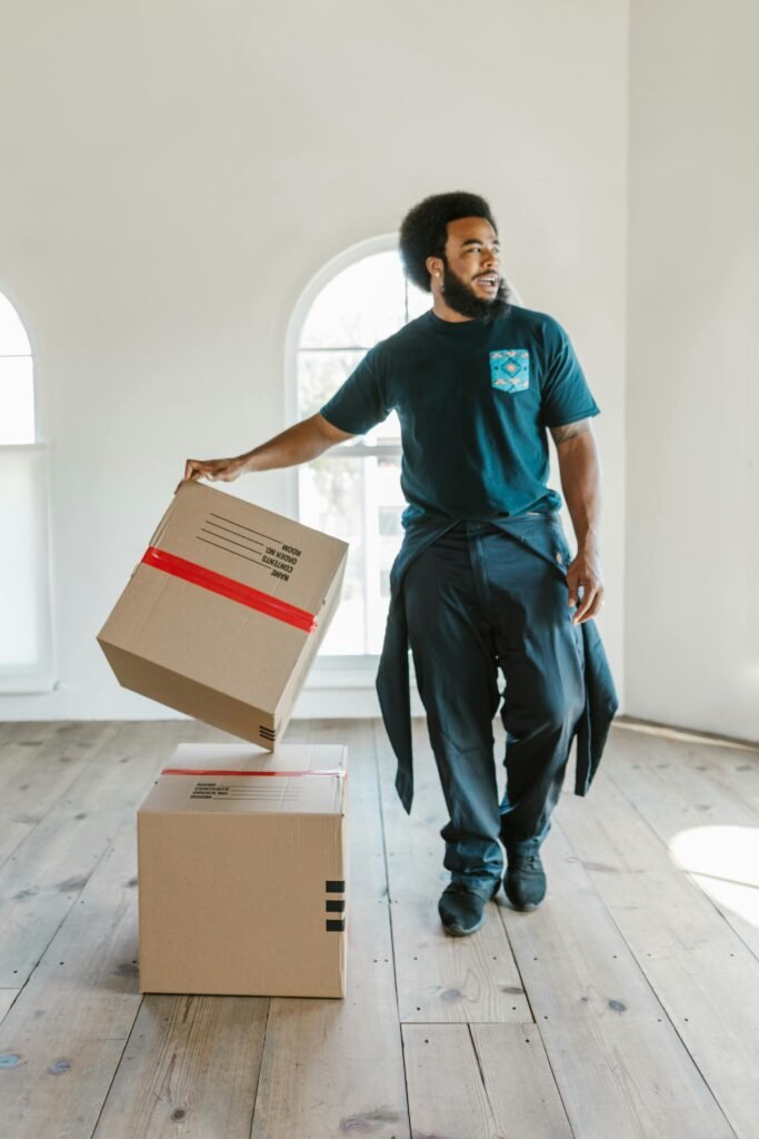 A mover carefully handles boxes in a bright, empty room on moving day.